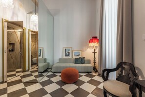 A modern living room with a checkered floor, a sofa set, a red lamp, and a chair. - ARCO VECCHIO URBAN SUITE by EPOCA COLLECTION (Lecce)
