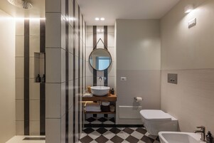 Un baño moderno con un espejo grande, un lavabo independiente, un inodoro y una zona de ducha.