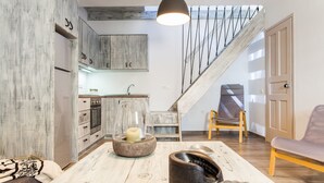 Una cocina moderna con armarios de madera, horno empotrado y comedor con mesa de madera.