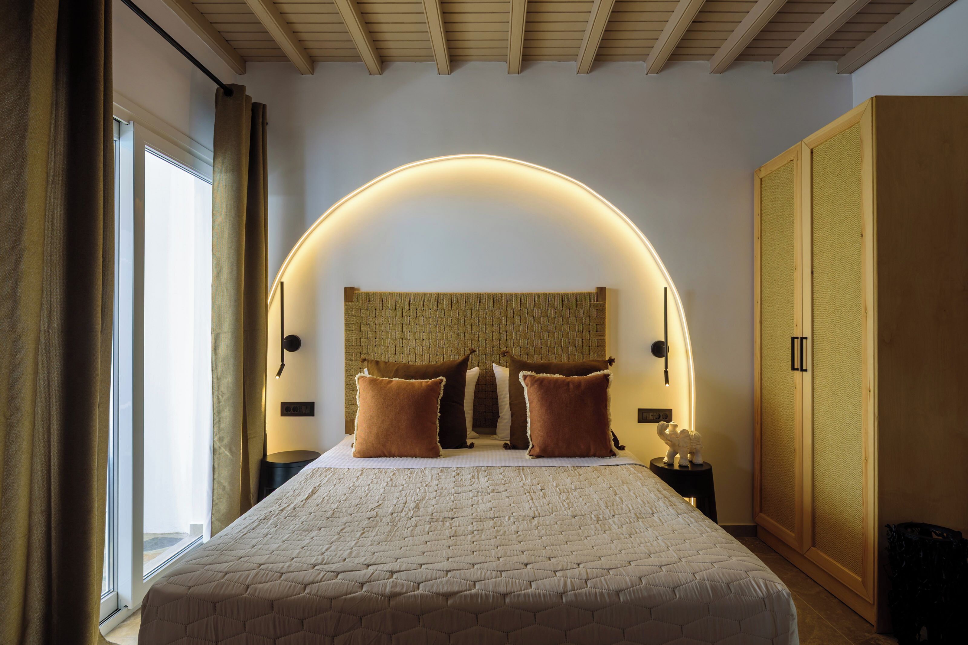 A bedroom with a large bed, a curved ceiling, and a wardrobe.