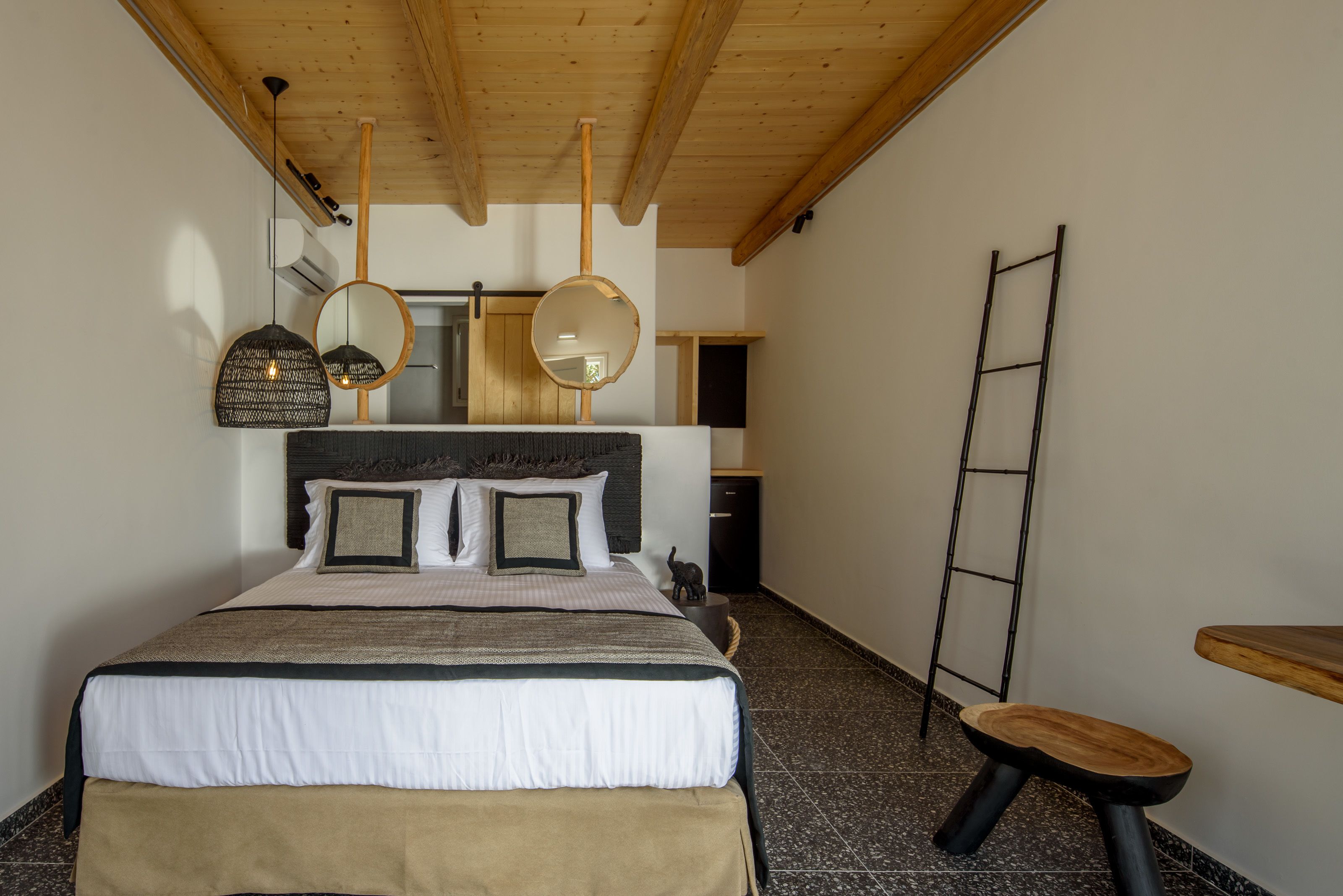 A bedroom with a bed, bedside tables, a wooden ladder, and a mirror.