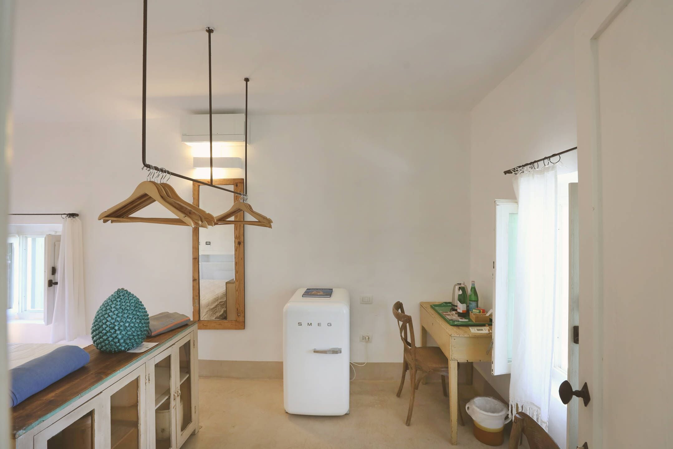 A compact kitchen with a white refrigerator, wooden furniture, and a hanging light fixture.