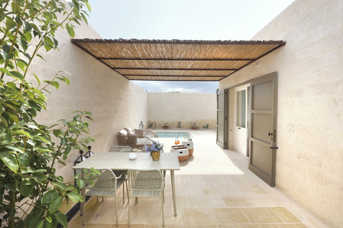 Un patio techado con mesa y sillas, una piscina pequeña y una puerta que da a otra habitación.