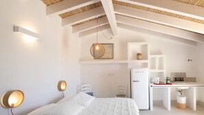 Ein Schlafzimmer mit einem Bett, Nachttischlampen, einem Schreibtisch und einer Küchenzeile.
