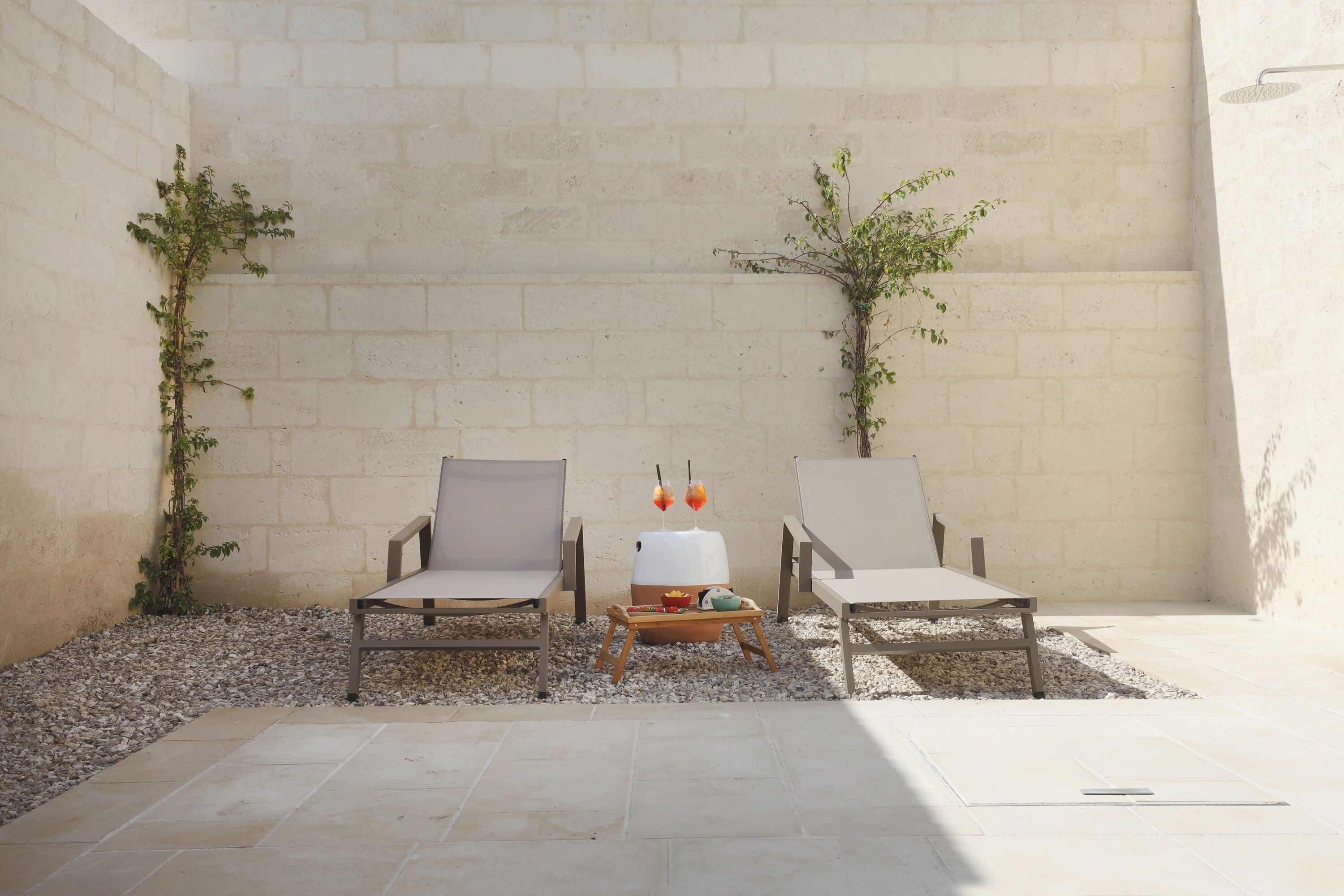 Une terrasse avec deux chaises, une petite table et un distributeur d’eau blanc.