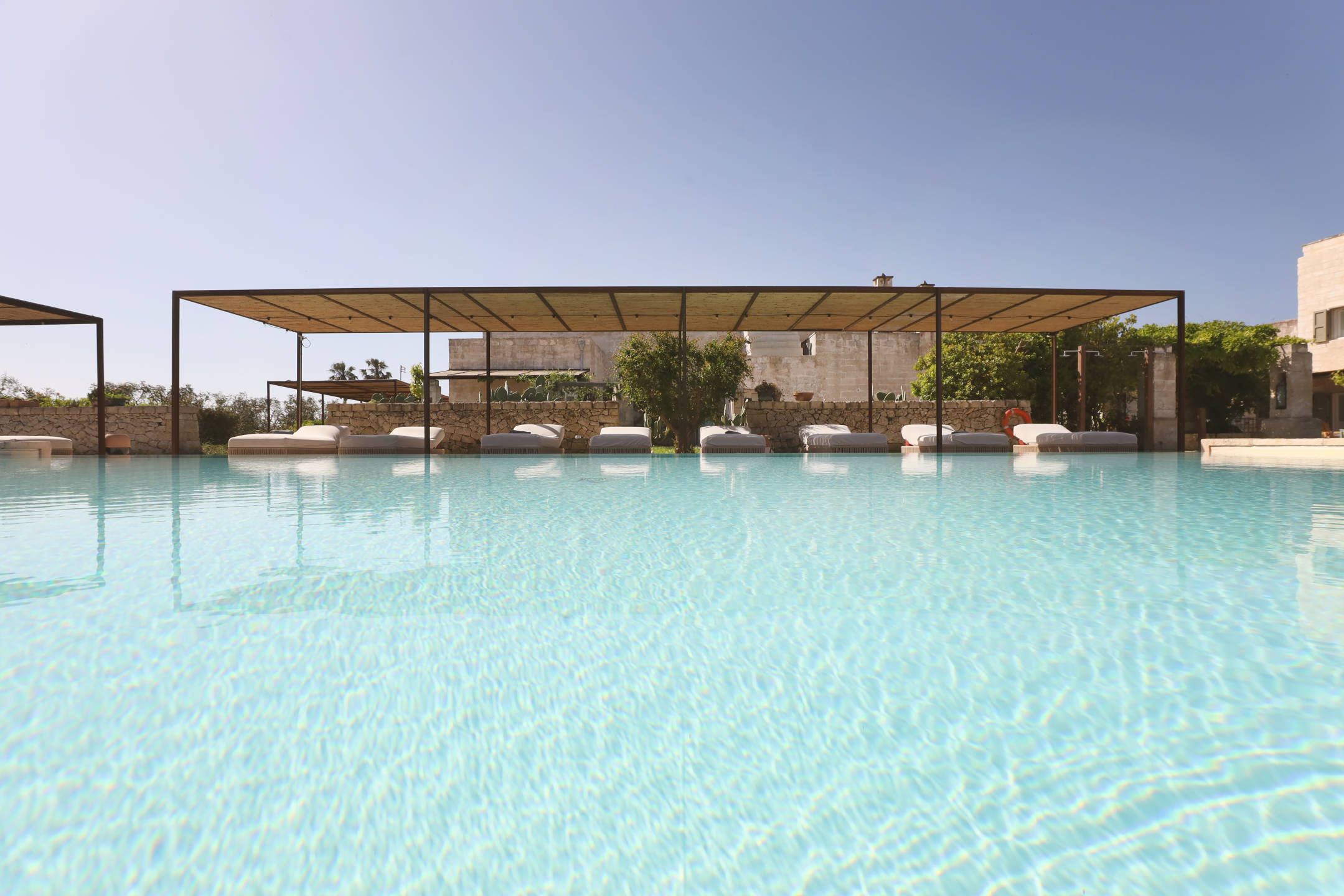 Una piscina cristalina con sillas de descanso y una zona de estar techada.