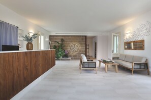 A modern living room with a wooden reception desk, a sofa, and a coffee table. - Masseria Borgo Sentinella (Melendugno)