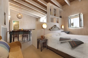 A bedroom with a bed, bedside tables, a desk, chairs, and a window.
