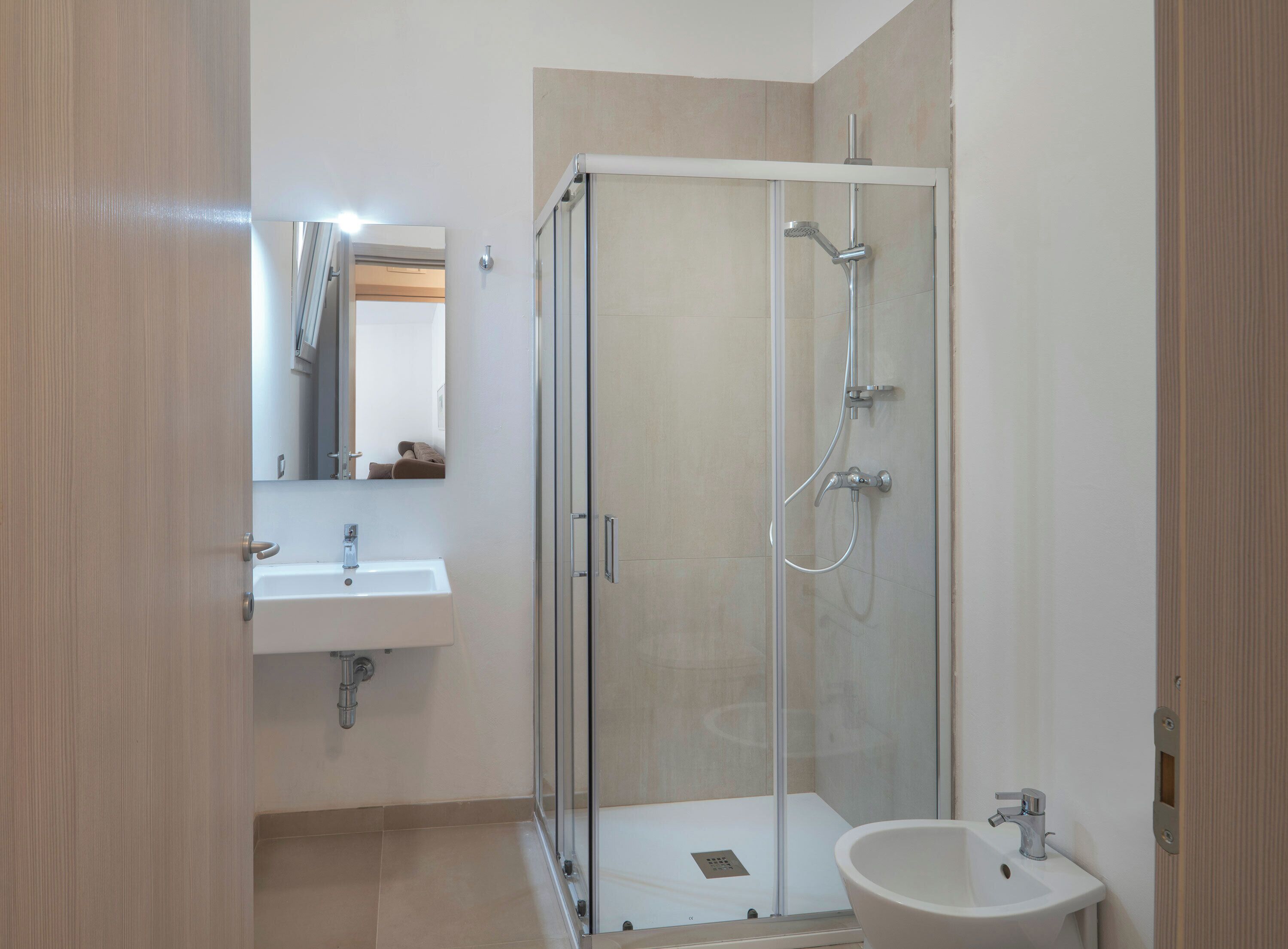Un baño moderno con ducha envuelta en vidrio, un lavabo y un espejo.