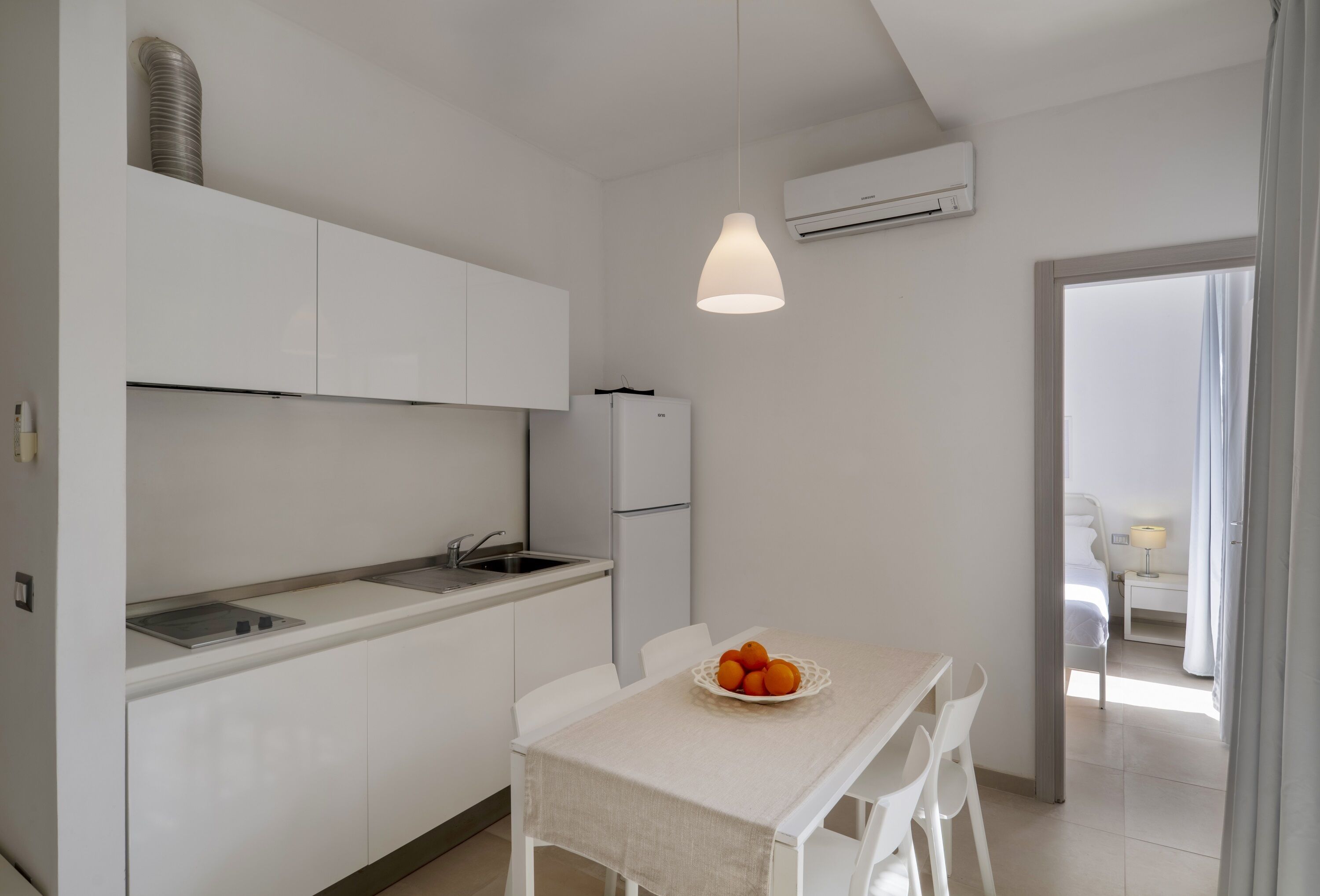 A modern kitchen with white cabinets, a sink, and a dining area with a table and chairs.