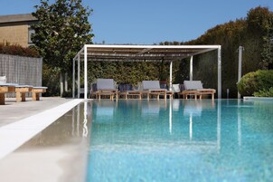 Una piscina al aire libre, sillones reclinables de piscina