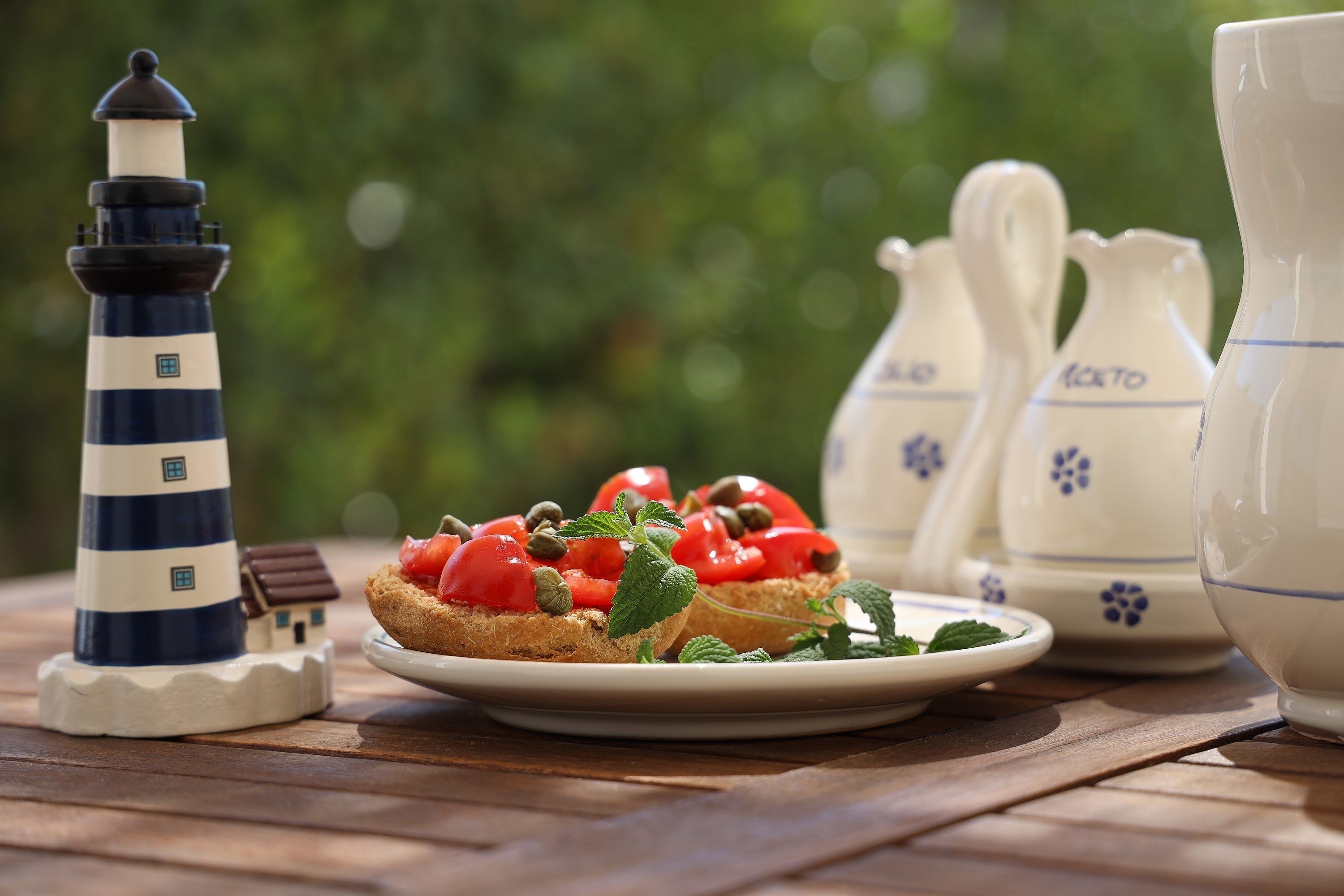 A table with a plate of food, a lighthouse model, and teapots.