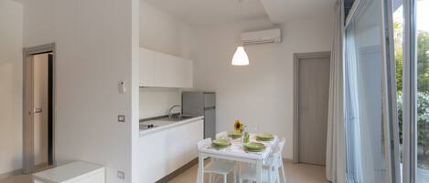 A modern kitchen with white cabinets, a dining table set with green plates, and a pendant light.