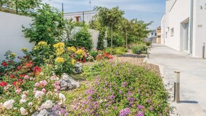 A garden with colorful flowers and a pathway leading to a building. - Salento Residence & Suite (Lecce)