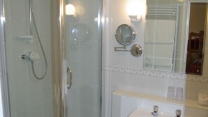 A modern bathroom with a glass-enclosed shower, a white sink, and a mirror above it.