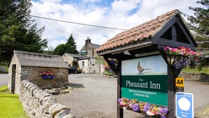 A sign for The Pheasant Inn, indicating it offers good food, accommodation, and traditional ales.