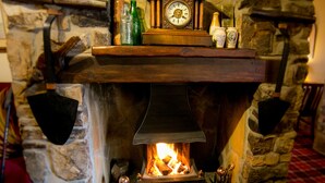 A stone fireplace with a mantel displaying a clock and various bottles.