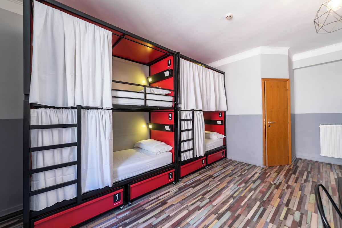 A dormitory room with bunk beds, numbered storage drawers, and a patterned floor.