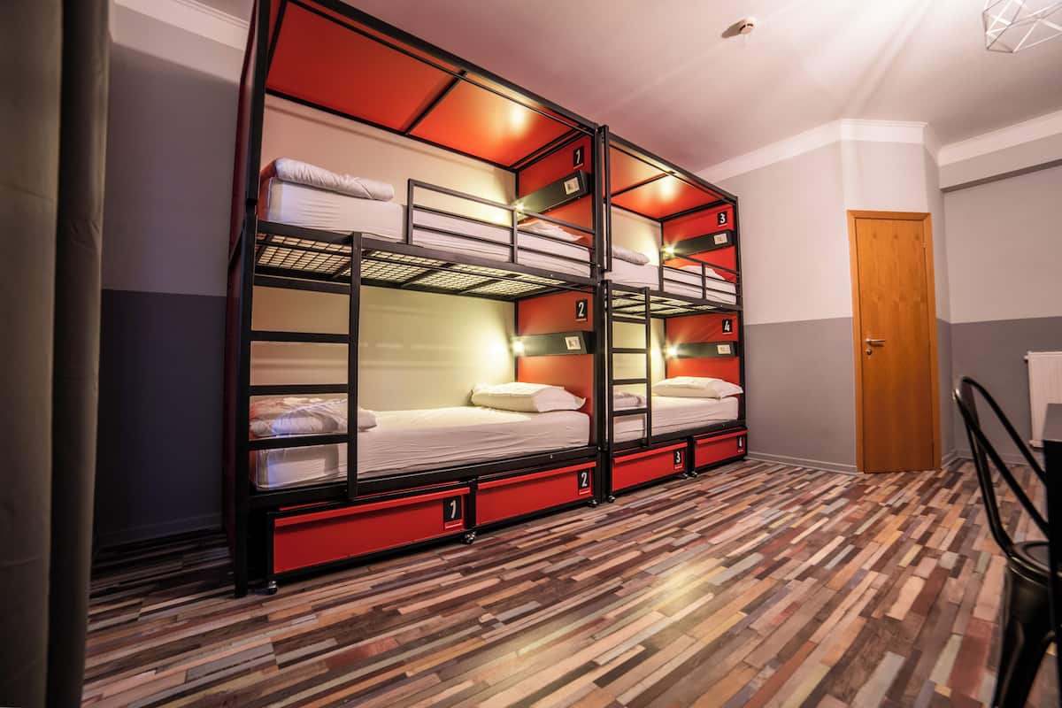 A bunk bed room with a wooden floor, a wooden door, and a staircase.