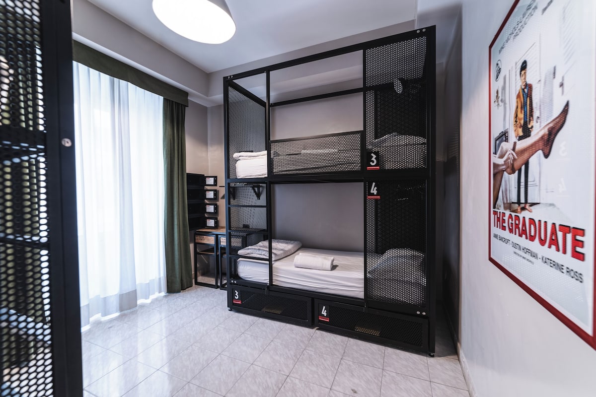 A room with a bunk bed, a desk, a chair, and a poster on the wall.