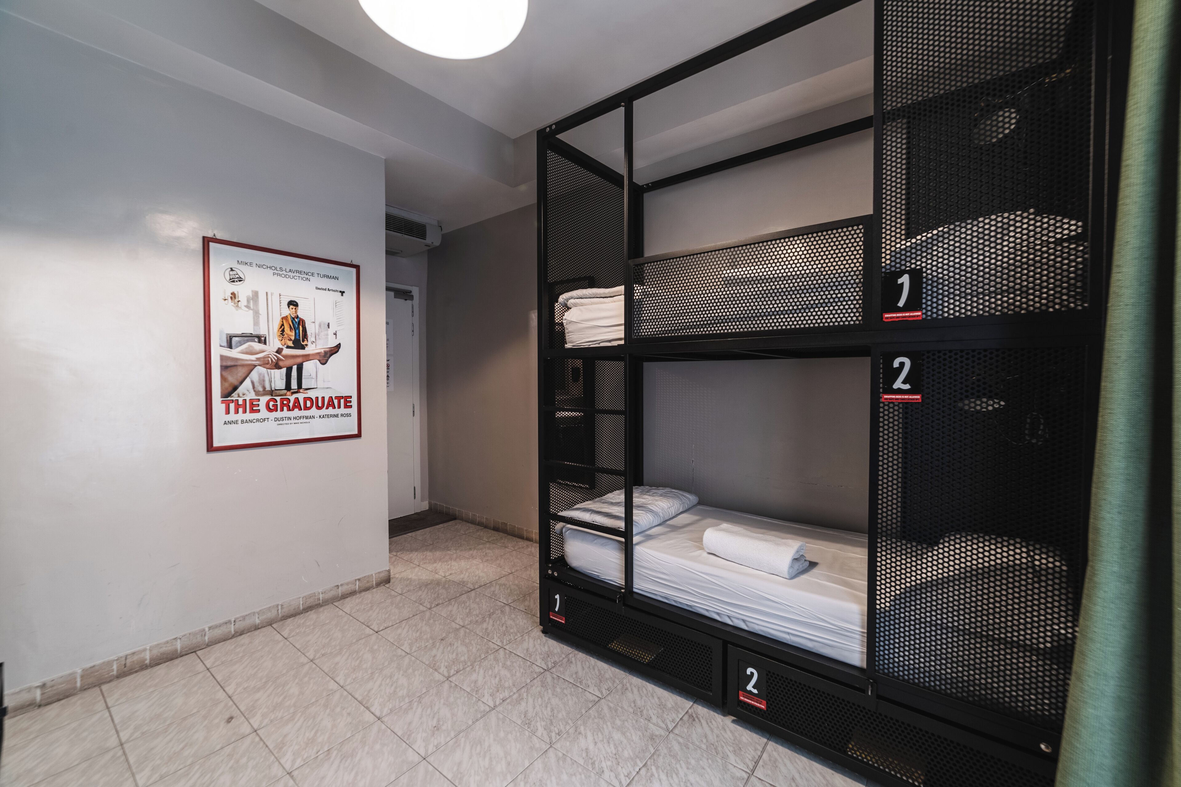A dormitory room with bunk beds, numbered compartments, and a poster on the wall.