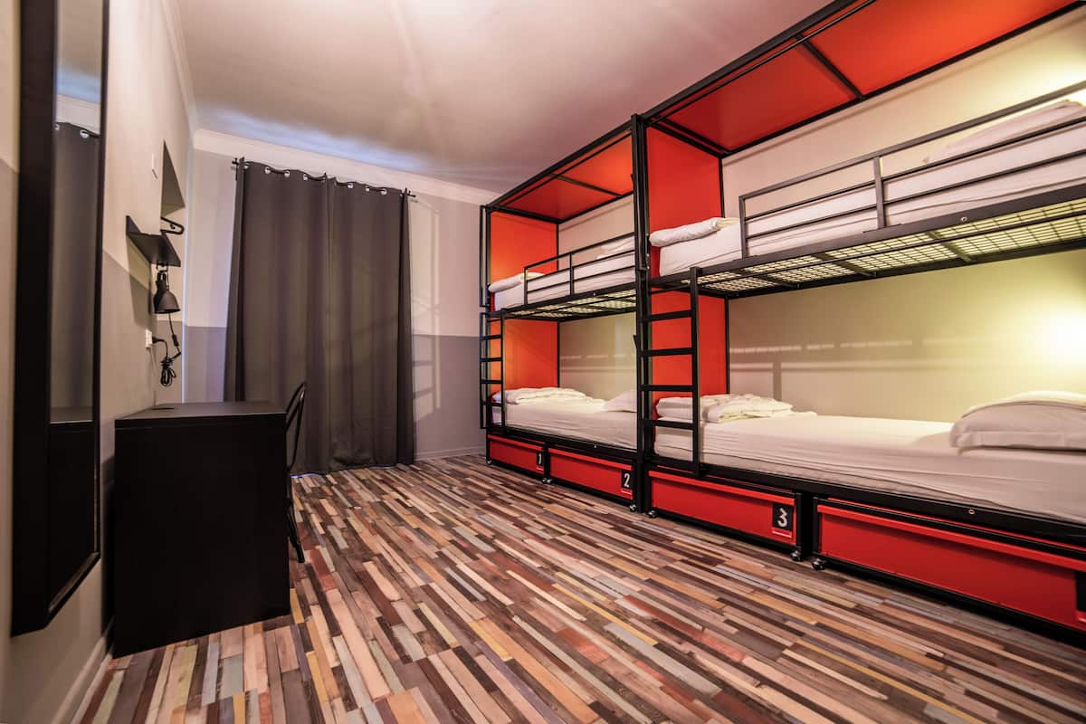 A room with bunk beds, a desk, and a patterned floor.