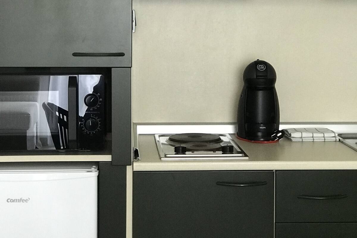 A compact kitchen with a microwave, coffee maker, and a small stove.