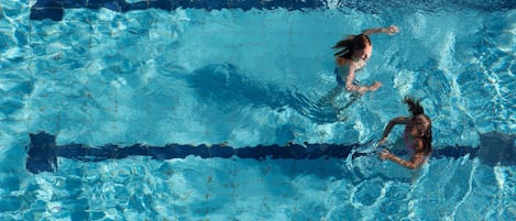 Una piscina al aire libre, sombrillas, sillones reclinables de piscina