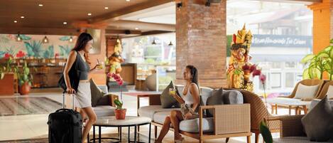 A spacious lobby with a modern design, featuring a seating area with sofas and a coffee table, and a large decorative pillar.