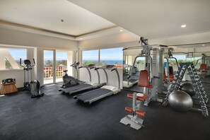 Un gimnasio con cintas de correr, elípticas y equipo de pesas.