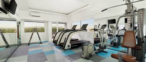 Un gimnasio con cintas de correr, bicicletas estáticas y máquinas de pesas.
