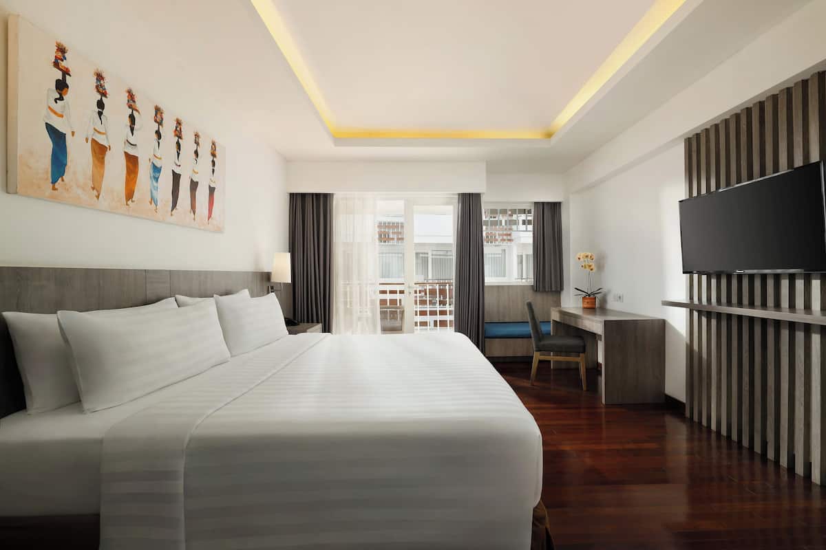 Une chambre d’hôtel moderne dotée d’un grand lit, d’un bureau, d’une télévision à écran plat et d’un tableau au mur.
