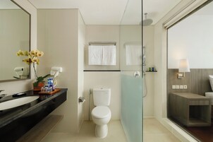 Et moderne badeværelse med bordplade i sort, toilet i hvidt, brusekabine i glas og et stort spejl.