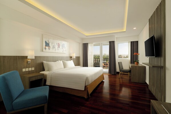 A modern hotel room with a large bed, a desk, a TV, and a view of the outdoors.