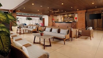 A spacious lobby with a high ceiling, wooden ceiling panels, and a reception desk with a red lamp.