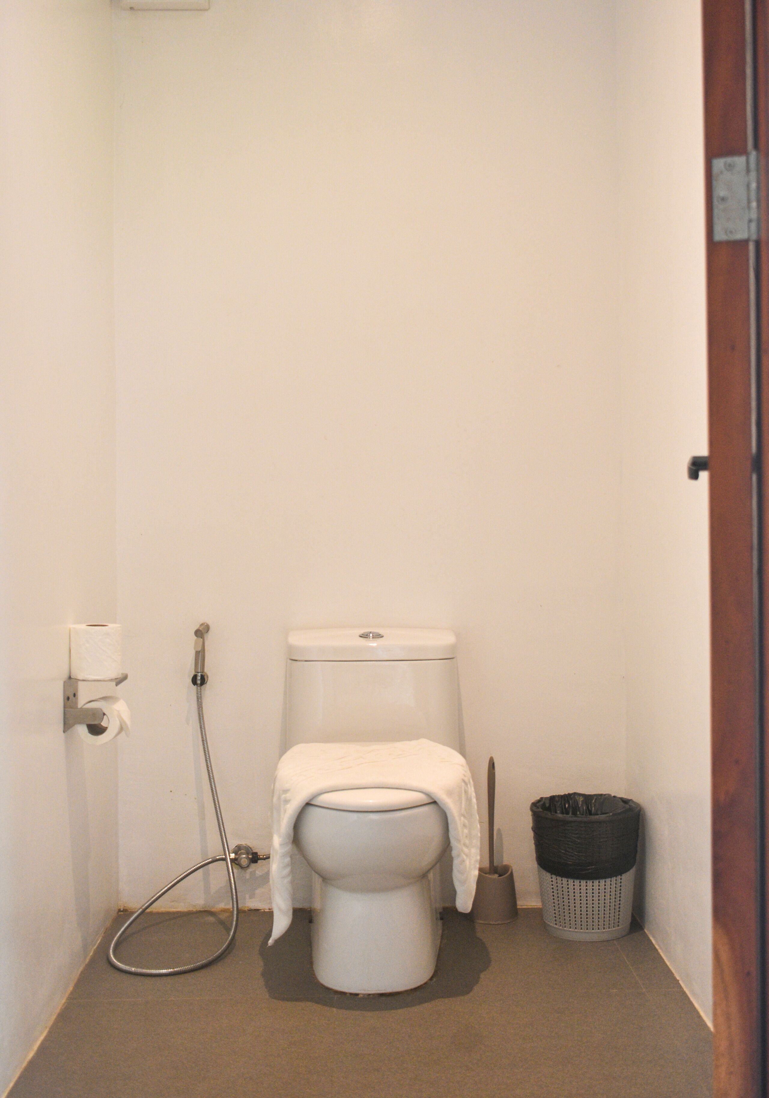 Un baño pequeño y limpio con inodoro, ducha y un cubo de basura.