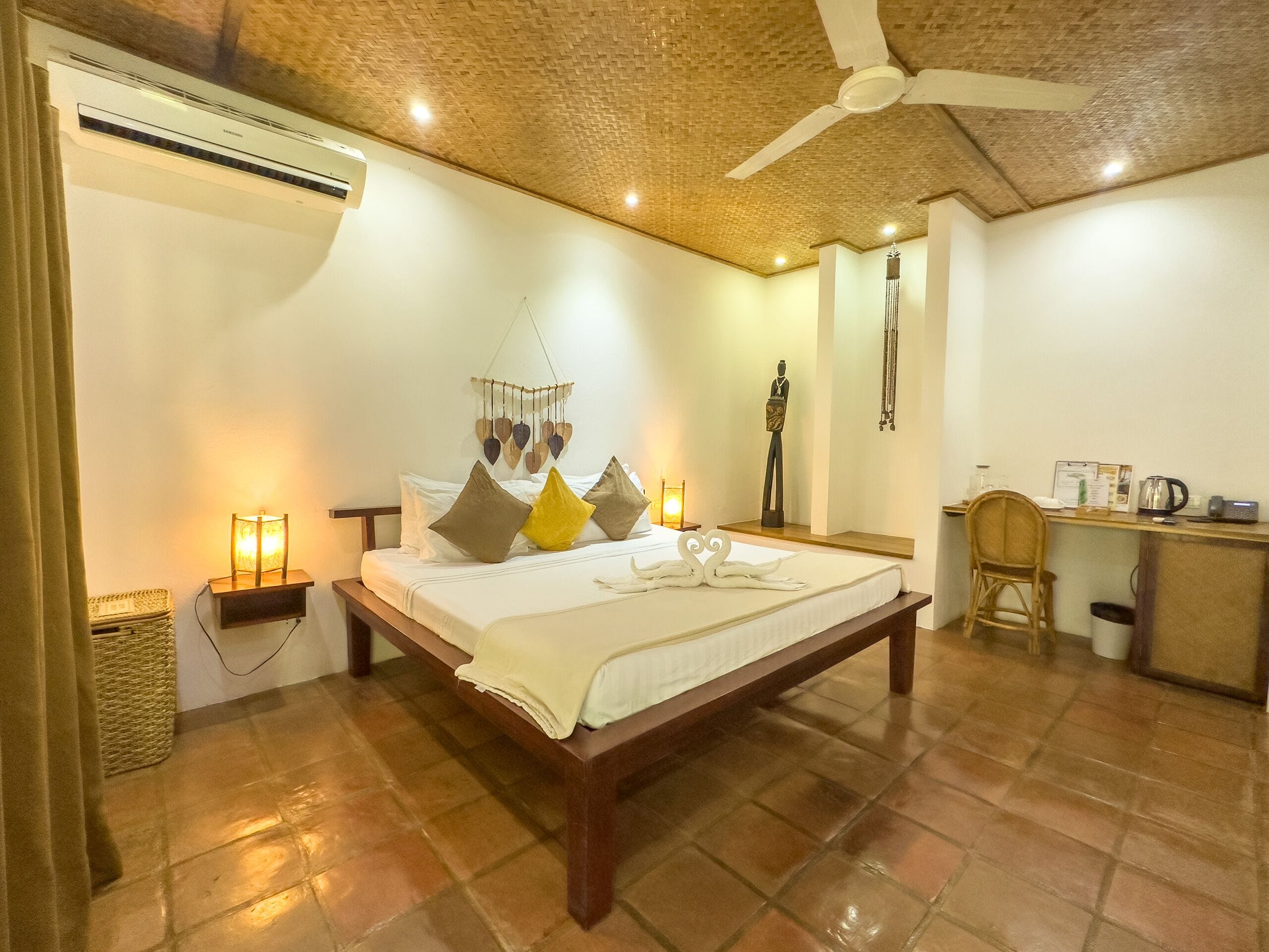 A spacious bedroom with a large bed, a desk, and a ceiling fan.
