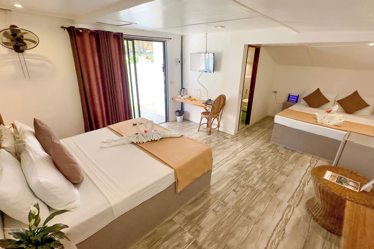 A hotel room with a bed, a desk, a chair, a TV, and a small balcony.