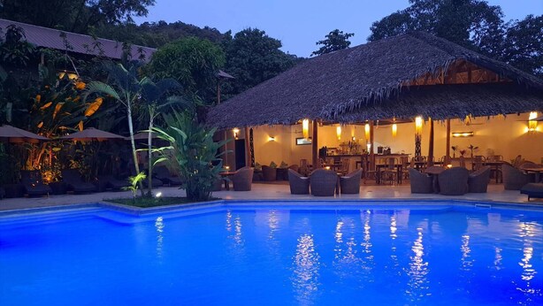 A poolside area with a thatched-roof structure, lounge chairs, and a bar area. - El Nido Coco Resort (El Nido)