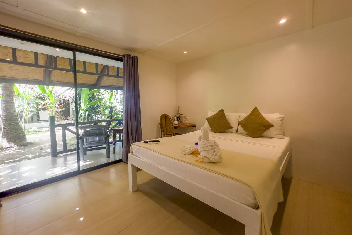 A hotel room with a bed, a desk, and a view of the outdoors.