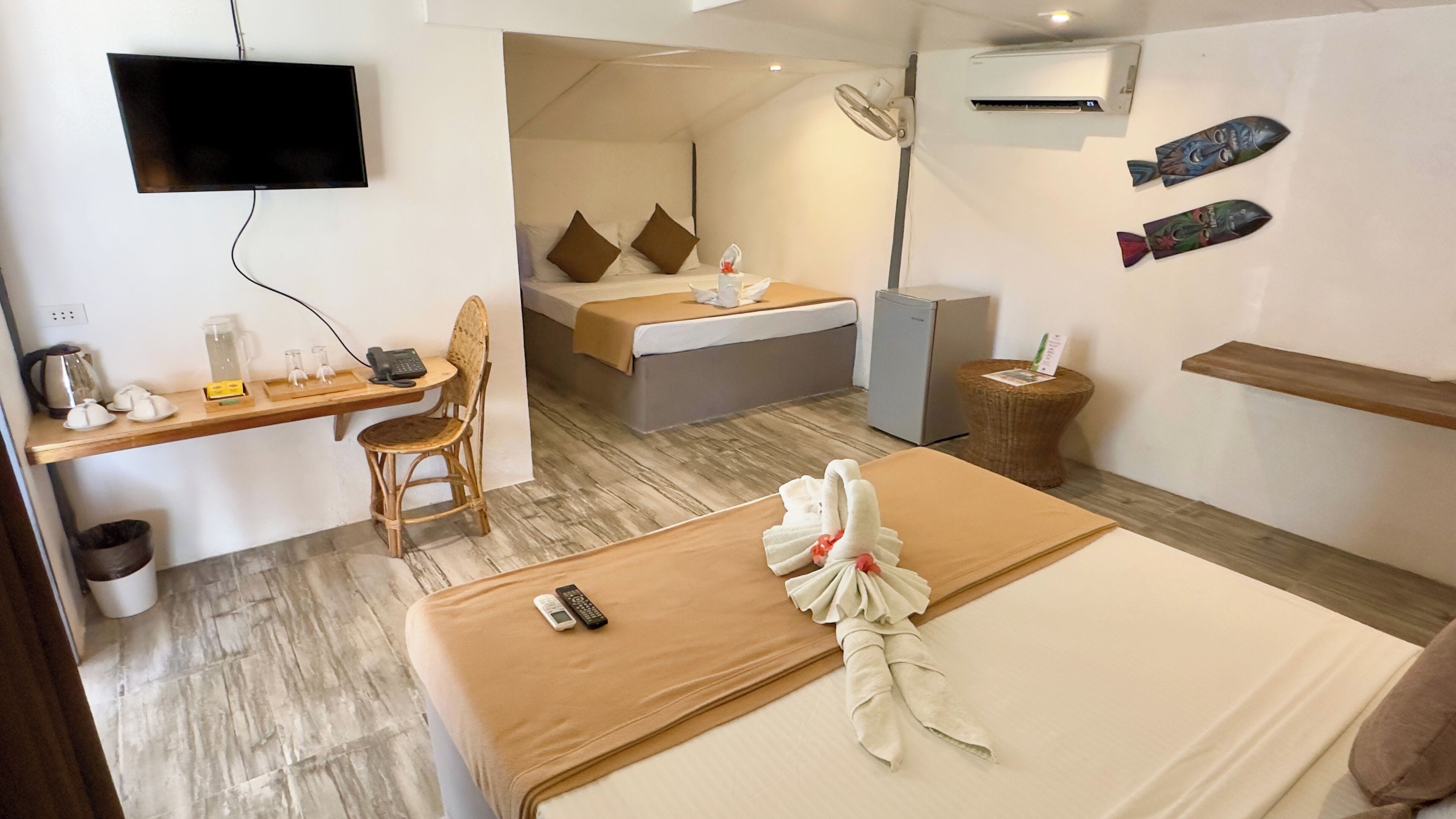 A hotel room with a bed, a desk with a chair, a television, a minibar, and a small refrigerator.
