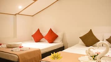 A hotel room with two beds, each with a different pillow color, a swan decoration on one bed, and a bedspread with a logo.