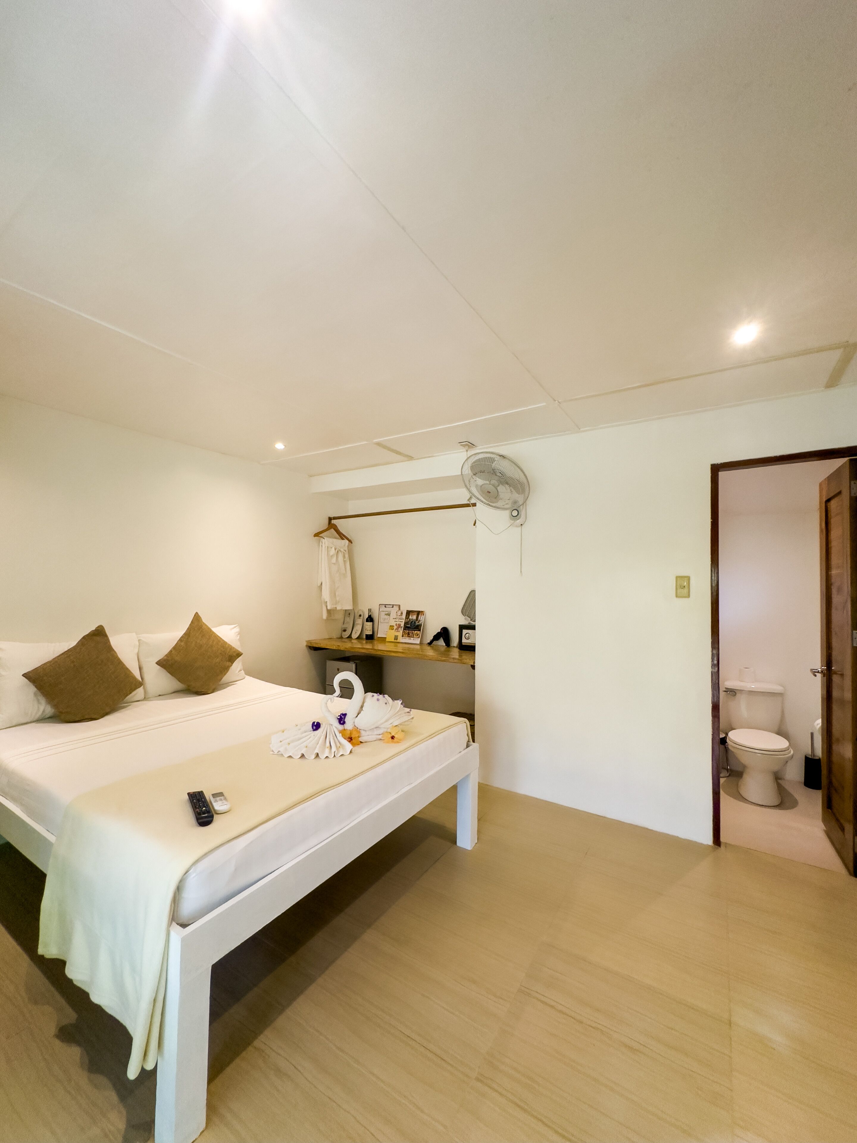 A bedroom with a bed, bedside table, and a fan.
