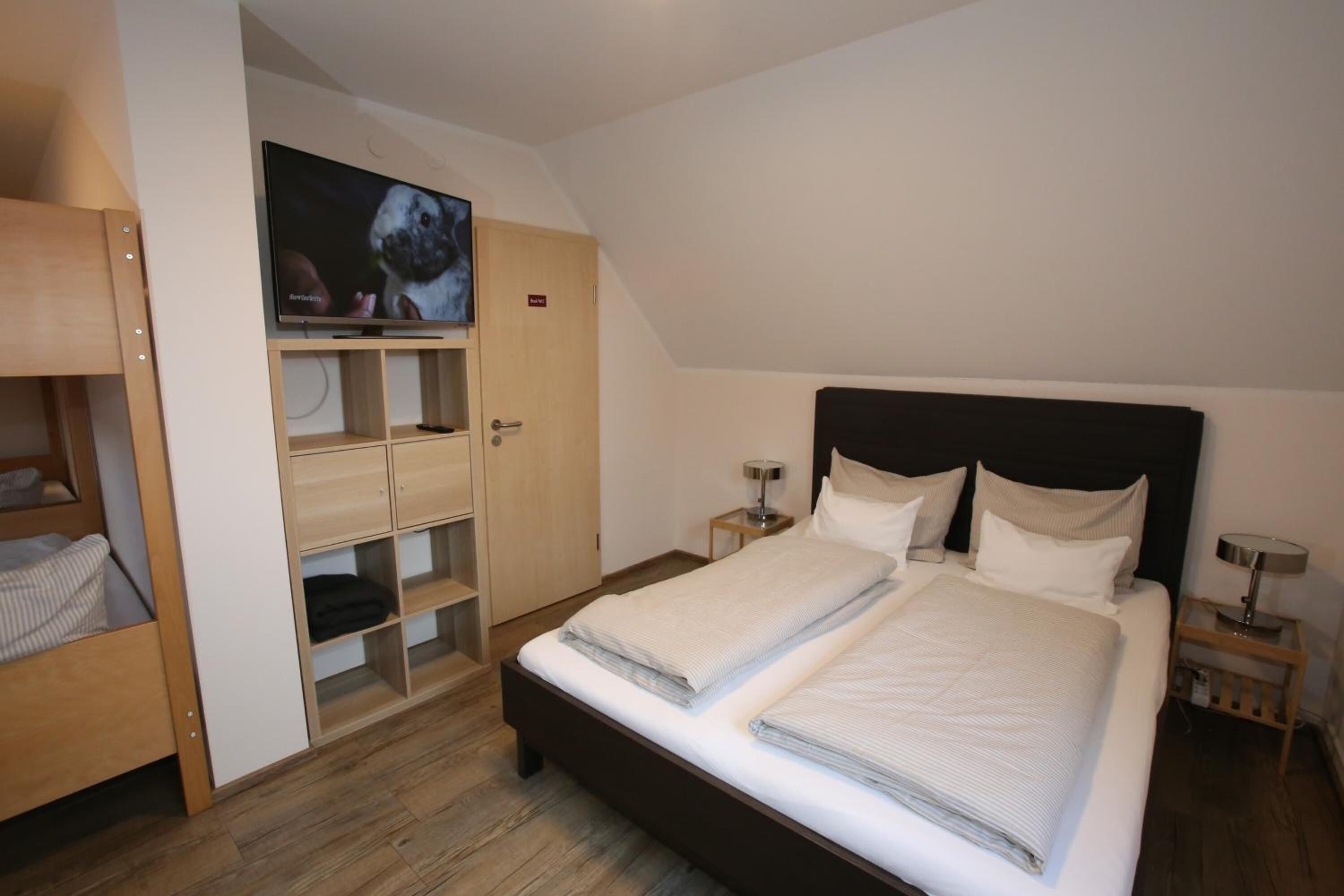Een slaapkamer met een bed, een aan de muur bevestigde televisie en een kledingkast.