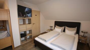 Een slaapkamer met een bed, een aan de muur bevestigde televisie en een kledingkast.