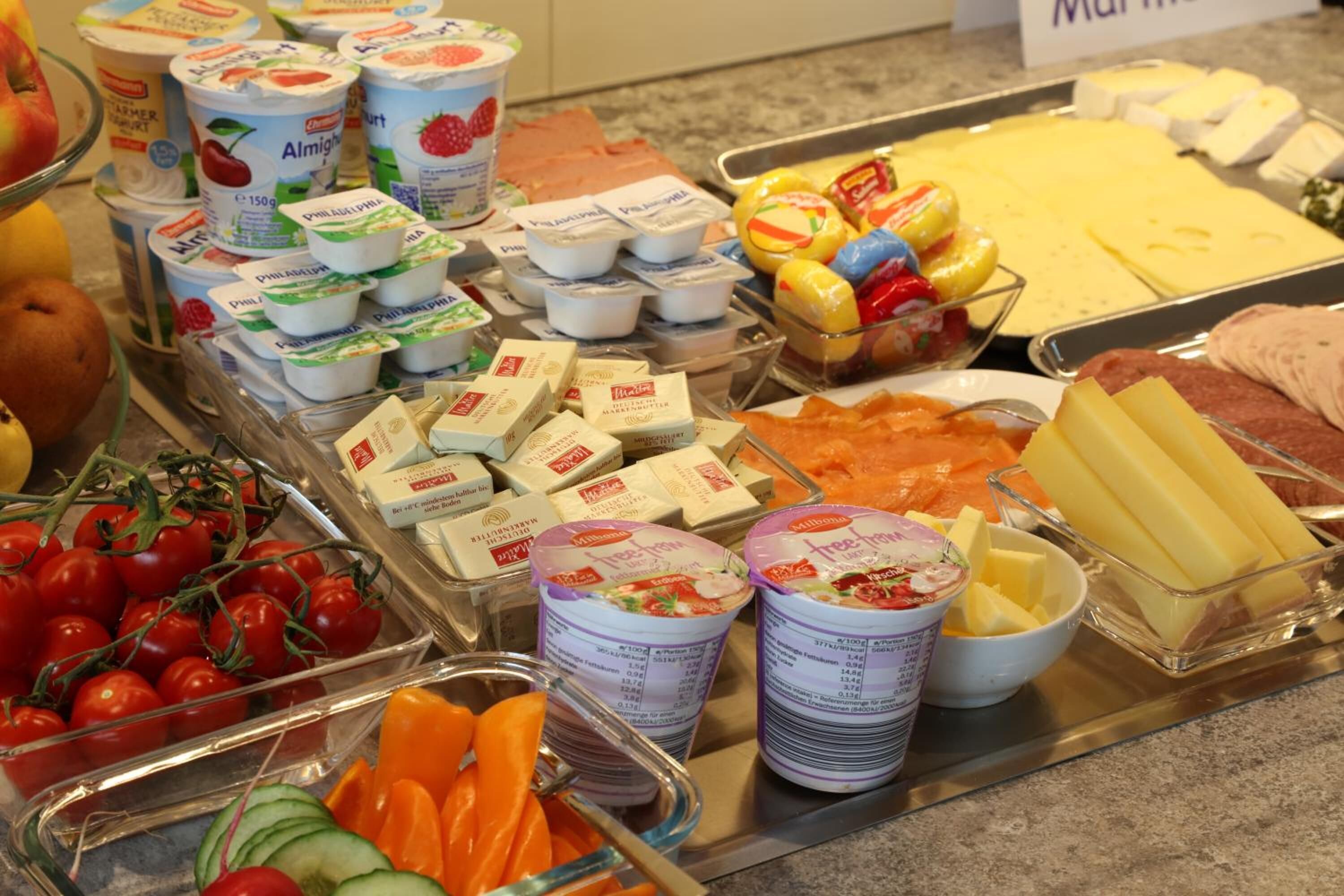 Un bufé con diversas opciones de comida, incluyendo yogur, queso y frutas.