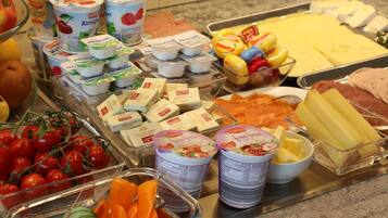 Un bufé con diversas opciones de comida, incluyendo yogur, queso y frutas.
