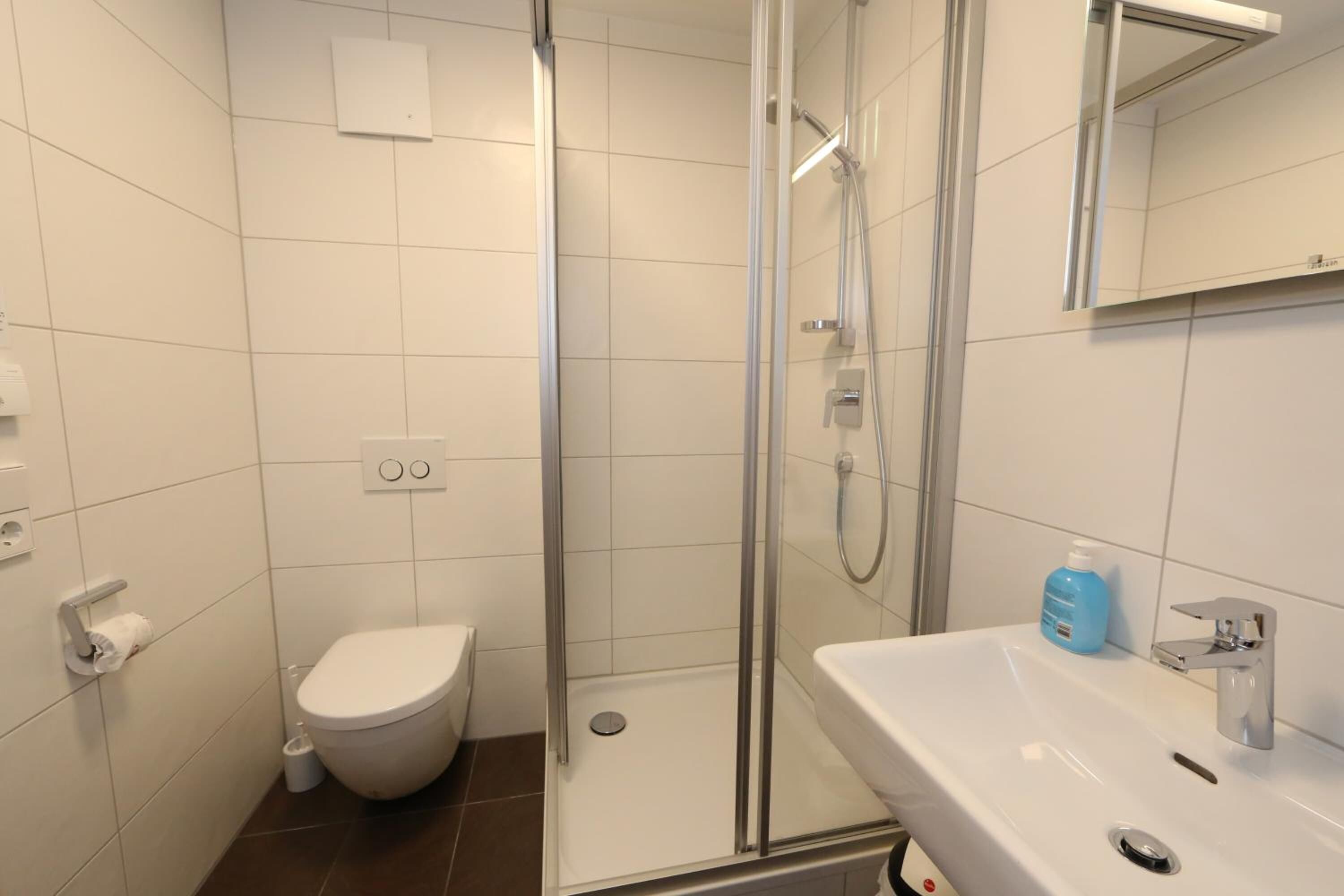 A modern bathroom with a toilet, shower, and sink.