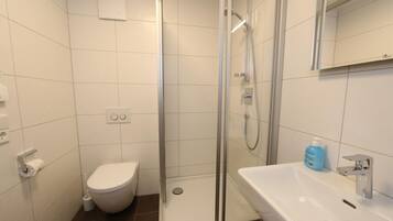 A modern bathroom with a toilet, shower, and sink.