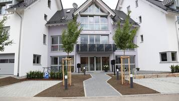 A two-story building with a central entrance, a parking sign, and a wheelchair-accessible sign.